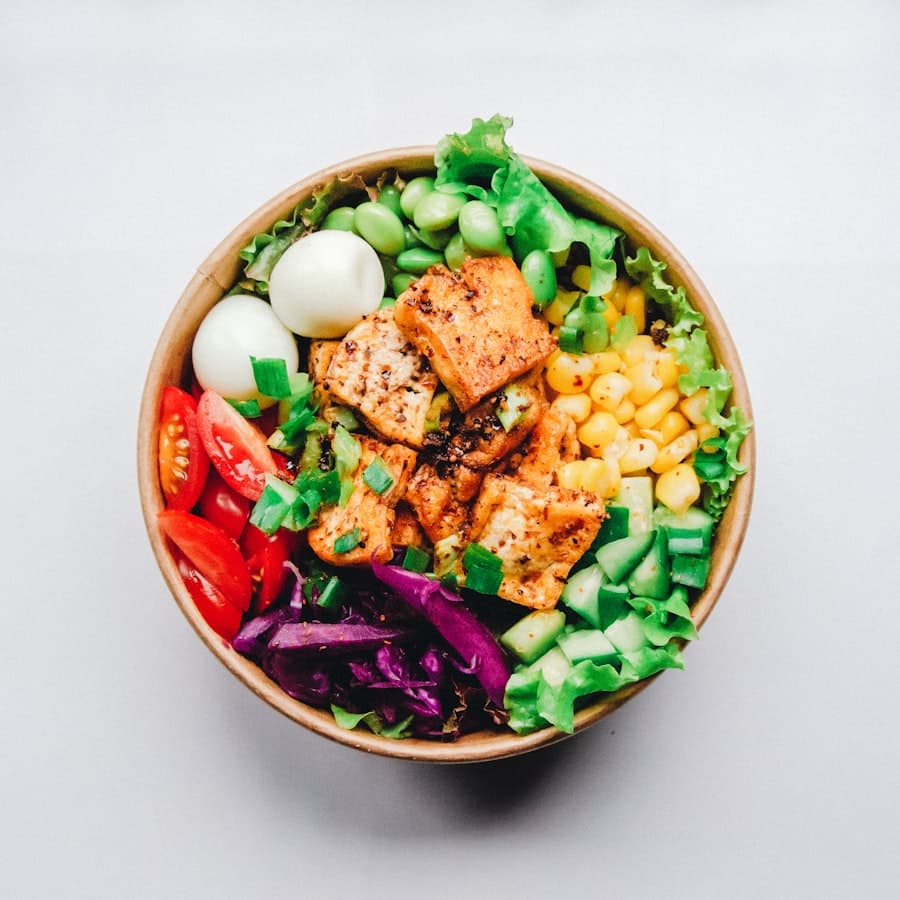 Top-down photo of a chicken power bowl with corn, edamame, egg and fresh vegetables
